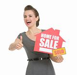 Happy realtor with home for sale sold sign showing thumbs up isolated