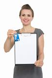 Happy female realtor holding blank clipboard and keys isolated