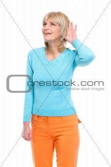 Middle age woman holding hand near ear and trying to hear something