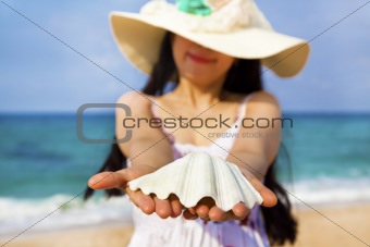 smiling young woman holding shell on the beach
