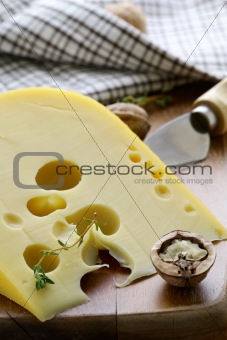 large piece of cheese varieties Maasdam on cutting board