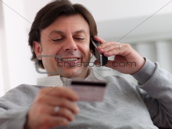 adult man shopping from home with telephone and credit card