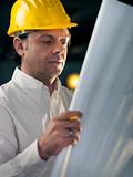 Adult businessman working as engineer holding blueprints