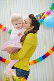 Mother kissing baby on birthday celebration party
