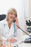 Smiling middle age doctor woman speaking phone