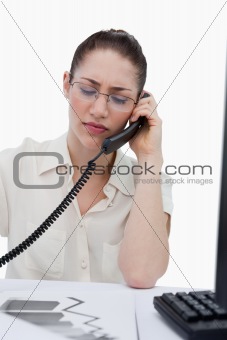 Portrait of a young manager making a phone call while looking at statistics