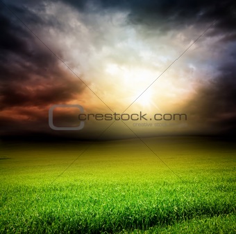 dark sky green field of grass with sun light 