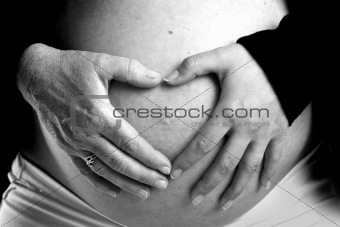 Old and young hand on pregnant belly