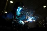 Welder welding a metal part in an industrial environment