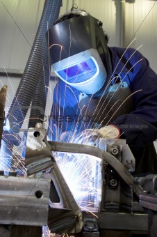 Manual welder welding in an industrial environment