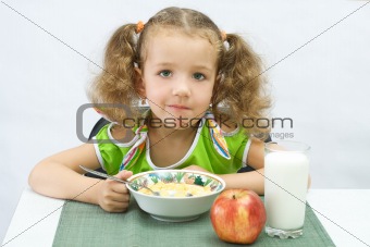 The girl has breakfast corn flakes with milk, over white