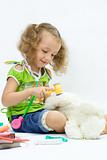 The girl plays in the doctor with toy tools, over white