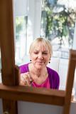 Happy elderly woman painting for fun at home