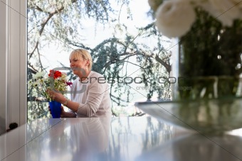 Elderly caucasian woman with flowers at home