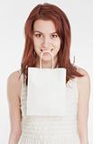 Young woman holding a white shopping bag in her mouth