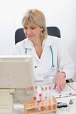 Portrait of smiling middle age doctor woman working on computer