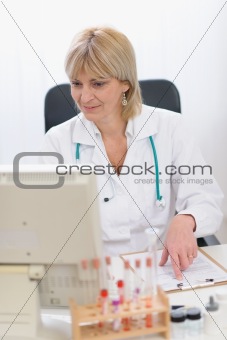 Portrait of smiling middle age doctor woman working on computer