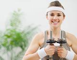 Portrait of happy fitness woman holding dumbbells