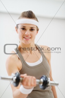 Young woman lifting dumb-bell in the gym