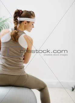 Woman sitting on fitness ball back to camera and looking on copy space