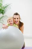 Portrait of smiling mother and baby behind fitness ball