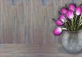 Purple tulips in a wase wooden texture background