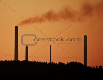 Industrial chimney stacks in natural landscape polluting the air