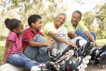 Grandparent With Grandchildren Putting On In Line Skates In Park
