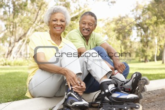 Senior Couple Putting On In Line Skates In Park