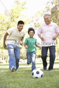 Grandfather With Son And Grandson Playing Football In Park