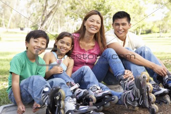 Family Putting On In Line Skates In Park