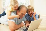 Grandfather AndGrandchildren Using Laptop At Home