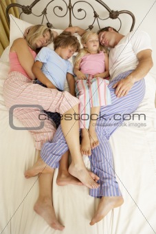 Family Relaxing On Bed At Home