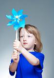 boy with long blond hair in blue top playing with a pinwheel 