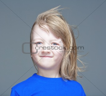 portrait of a boy with long blond hair smiling - isolated on gray