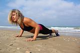 Beautiful woman at the beach, doing push-ups