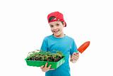 Boy with tomato seedlings in tray and small gardening spade