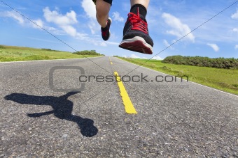 the legs and shoes of runner in action on the road