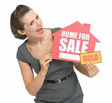 Happy real estate owner with home for sale sold sign