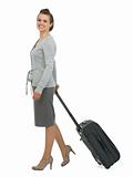 Happy traveling woman with suitcase walking sideways