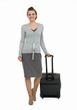 Happy traveling woman with suitcase making step forward