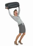 Traveling woman raising suitcase above head