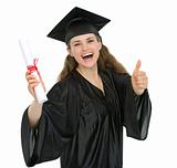 Smiling graduation woman with diploma showing thumbs up