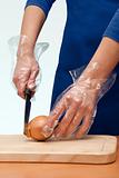hands in plastic gloves cut the onion