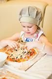 Little girl adding cheese in pizza
