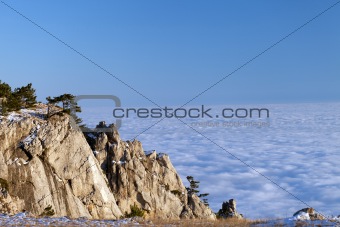 Sunlit cliffs and sea in clouds
