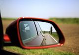 Road and trees reflected in rear-view mirror