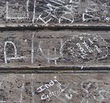 children graffiti in white paint marker on wooden bench