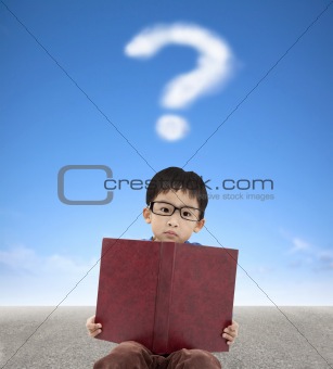 little boy holding book and question mark cloud background