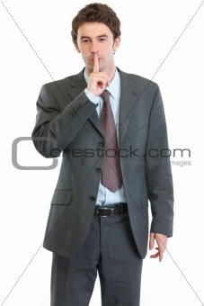 Modern businessman showing shh gesture
